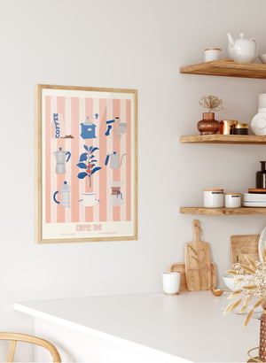 L’affiche "Coffee Time – Les Iconiques" en version incarnadin mise en valeur au-dessus d’un plan de travail cosy avec cafetière et mugs assortis.
